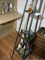 Overall view of three-tier metal stand holding assorted perfume bottles and jars