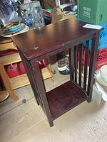 Front three-quarter view of dark reddish-brown side table with slatted sides and lower shelf