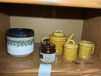 All items on shelf: bamboo-style teapot, sugar bowl, creamer, stoneware planter, J. R. Kane jar