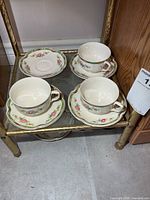Three teacups and four saucers on metal shelf
