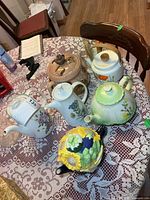 Group view of six teapots and napkin holder on table