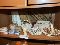 Shelf showing overall assortment of trinket boxes, baskets, eggs and crate