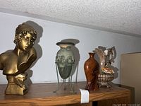 Group view of plaster bust and three vases on shelf