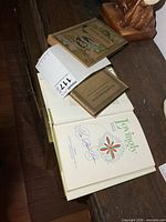 All three books stacked, one opened to signed page