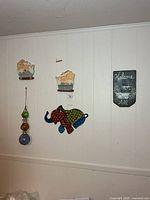 Group shot showing all items hung on wall: two bathroom plaques, hanging glass balls, mosaic elephant, slate welcome sign