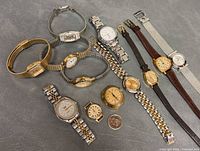 Group shot of twelve assorted vintage women’s watches with coin for scale