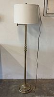 Full view of brass floor lamp with shade