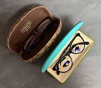 Two eyeglasses in open branded cases