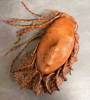 Front view of leather mask showing facial features, braided hair, and collar