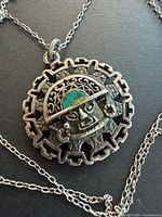 Front view showing sun pendant, mask design, enamel detail and chain