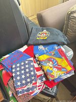 Stack of assorted bandanas showing Mickey Mouse, American flag, blue slogan print and others