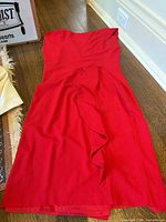 Strapless red ruffle sheath dress lying flat on floor