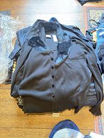 Stack of garments topped by black faux fur collar cardigan