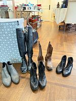 Group of six pairs of boots/booties on wood floor
