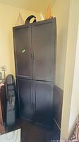 Front view of tall dark brown cupboard beside furniture