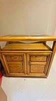 Front view of wooden cabinet showing glass top, open shelf and doors