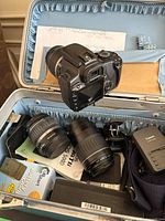 Open case showing camera body, two additional lenses, charger, strap and accessories