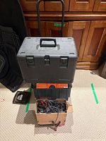 Ryobi toolbox on top of Motomaster charger with box of cables