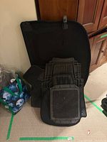 Stack of rubber floor mats and large protector leaning against cabinet