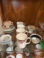 Cabinet shelf showing mugs, cups, saucers and stem glasses