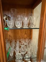 Two shelves filled with assorted clear crystal stemware and glassware