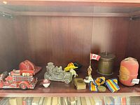 Shelf view showing fire truck model, helmets, medals, flag, brass container, fire extinguisher