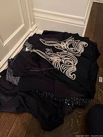 Pile of black dresses on floor showing quantity and color