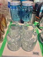 Two blue Ball mason jar goblets and four clear glass mugs inside green-tape boundary