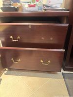 Front view of filing cabinet with both drawers closed showing brass handles and lock