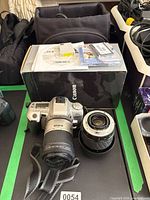 Minolta SLR with kit lens, loose lens, Canon box, bag and accessories visible