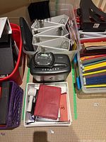 Group view showing shredder, label maker on top, binders, folders, holders, trays, notebooks in bins