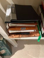 Stack of albums on shelf shows top brown faux-leather and decorative map cover
