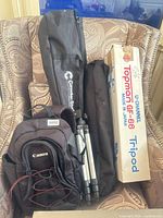 Overall lot showing Canon backpack, two black carry bags, boxed Tapan GF-6 tripod and compact tripod