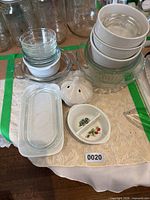 Group of glass and ceramic dishes on table within green taped boundary