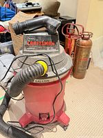 Full view of red Craftsman wet/dry vacuum showing hose, nozzle, caster base, capacity marking