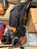 Bin containing ski boots, snow pants, baseball gloves, net, skates