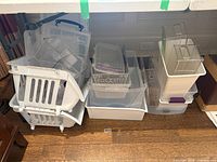 Group of stacked clear and white plastic bins and organizers under table