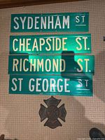 Four street signs mounted on wall showing Sydenham, Cheapside, Richmond, St George