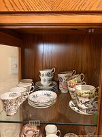 Display cabinet shelf holding assorted teacups and saucers