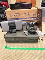 Group view of Technics changer, speaker dock, Denon items, Sears VCR box