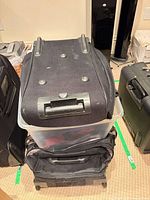 stacked black rolling suitcases atop clear bin