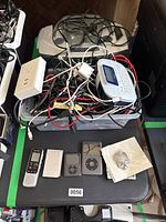 Overview showing bin of cables, Brother label maker, boombox and assorted small electronics on table