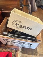 Cardboard box containing black velvet hangers and beige fabric storage bin