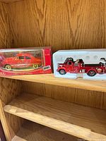 Both die-cast vehicles; boxed coupe and styrofoam-packed fire truck