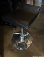 Top angled view of bar stool showing black seat and chrome pedestal base