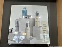 Square acrylic-mounted print showing Merle Norman skincare bottles on pedestals