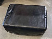 Top view of black vinyl ottoman showing overall shape and surface wear