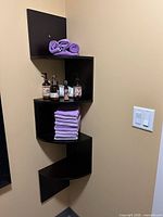 Full view of mounted 4-tier corner shelf with towels and toiletries for scale