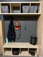 Full view showing bench with cubbies, upper 4-cubby shelf, two coat racks, and fabric bins.