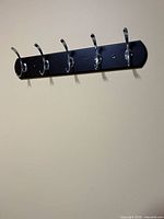 black wall-mounted board with five chrome double hooks